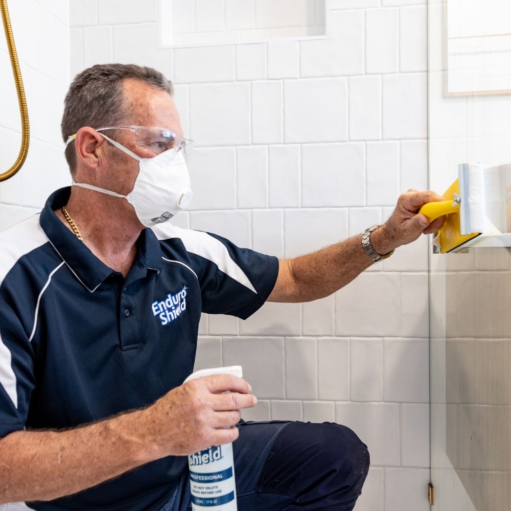man applying enduroshield to a shower door